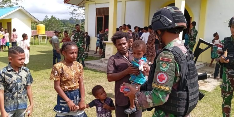 Keseruan Satgas Yonif 310/KK Bagikan Makanan Untuk Anak Di Perbatasan Usai Ibadah Bersama